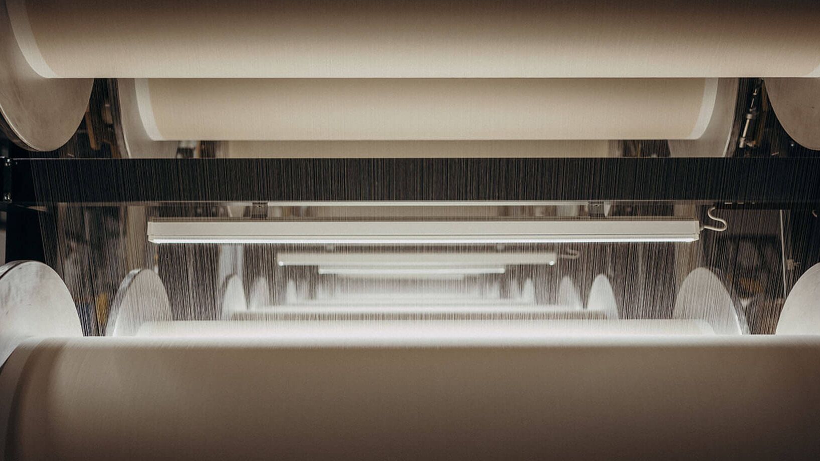 Mehrere große Papierrollen werden in einer industriellen Anlage für die Weiterverarbeitung vorbereitet.