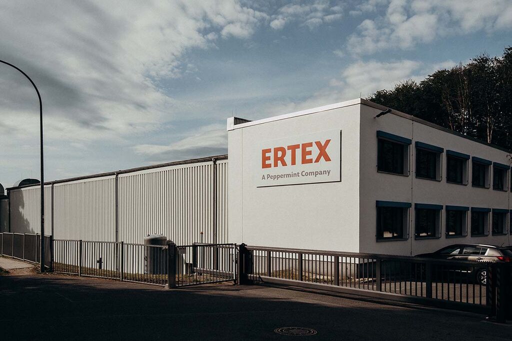The Ertex company building stands under a cloudy sky, showcasing its distinct signage and industrial architecture.