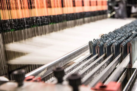 A close-up of a textile machine in operation, weaving intricate patterns with precision and speed.