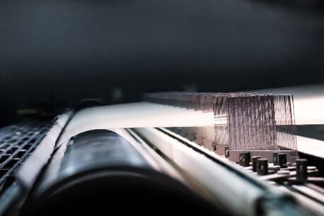 A close-up view shows a fast-moving paper printing process in a factory setting.
